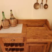 Credenza con cassetti e porta bottiglie in olmo spazzolato. Particolare del piano in marmo di Carrara e tagliere estraibile. Mobili country su misura Siena e Firenze